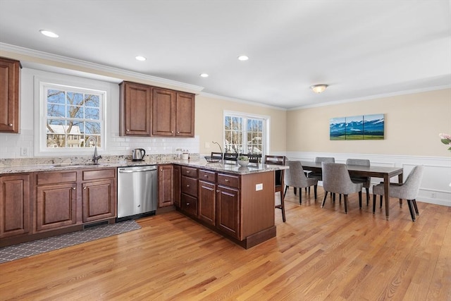 kitchen with light stone counters, a sink, plenty of natural light, a peninsula, and dishwasher