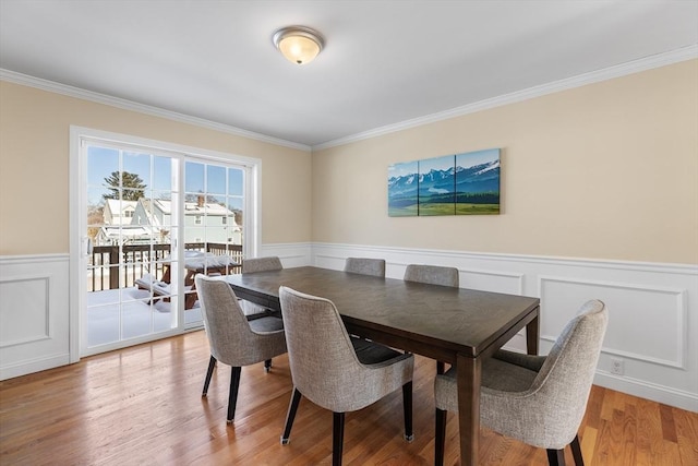 dining room featuring a wainscoted wall, ornamental molding, and wood finished floors