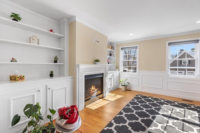 living area with visible vents, a healthy amount of sunlight, light wood-style flooring, and built in features