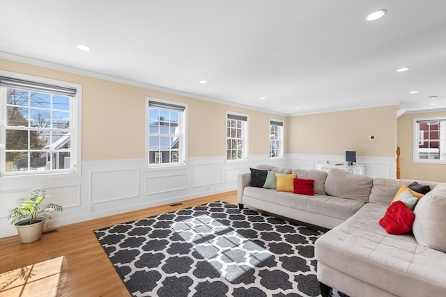 living room with ornamental molding, wainscoting, plenty of natural light, and wood finished floors