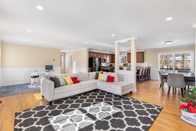 living area featuring a wainscoted wall, crown molding, light wood-type flooring, a decorative wall, and recessed lighting