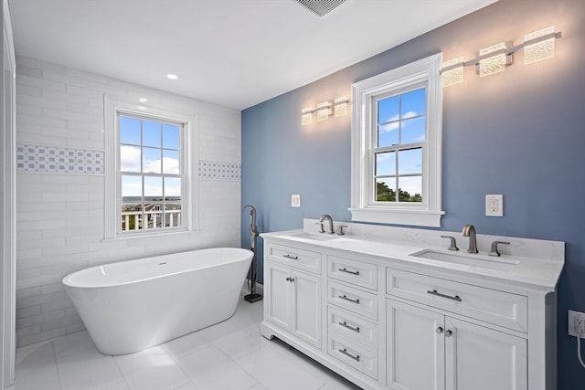 bathroom featuring vanity, a bathtub, tile patterned flooring, and tile walls