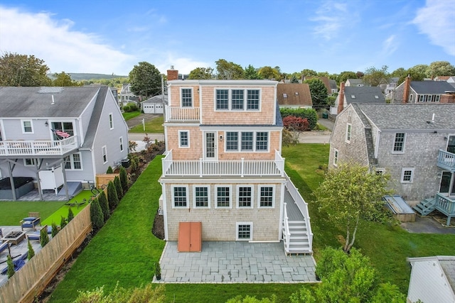 rear view of house with a balcony, a patio area, and a yard