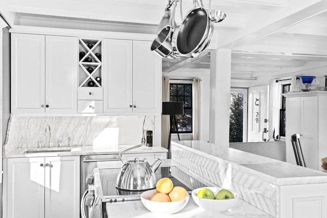 kitchen featuring beamed ceiling, sink, light stone counters, and white cabinets