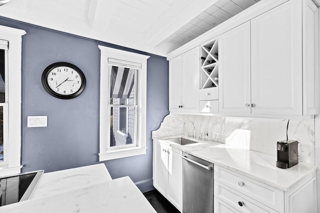 kitchen with light stone counters, beam ceiling, stainless steel dishwasher, and white cabinets