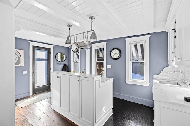 kitchen with pendant lighting, sink, beam ceiling, white cabinets, and dark hardwood / wood-style flooring