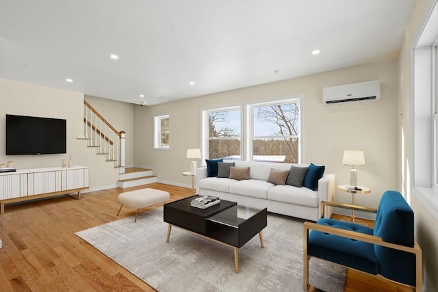 living room featuring wood finished floors, a wall unit AC, stairs, recessed lighting, and baseboards