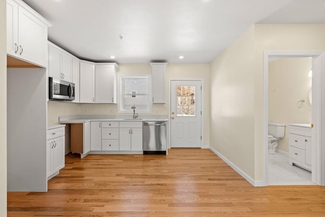 kitchen featuring stainless steel appliances, a sink, white cabinets, light countertops, and recessed lighting