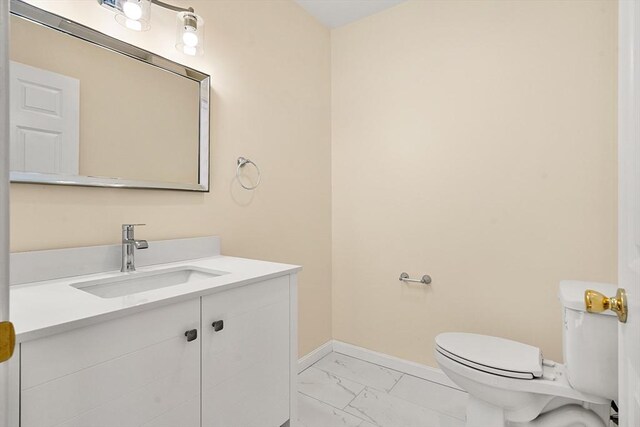 bathroom featuring marble finish floors, baseboards, toilet, and vanity