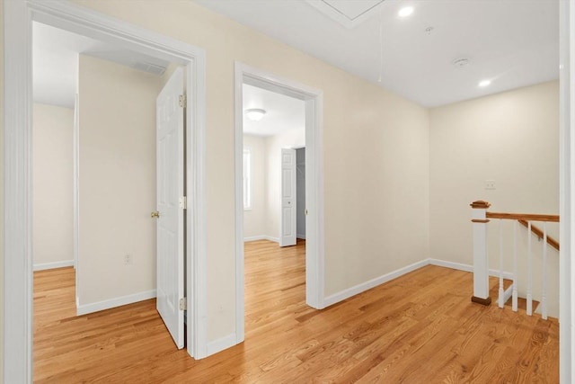 hallway featuring attic access, light wood finished floors, baseboards, recessed lighting, and an upstairs landing