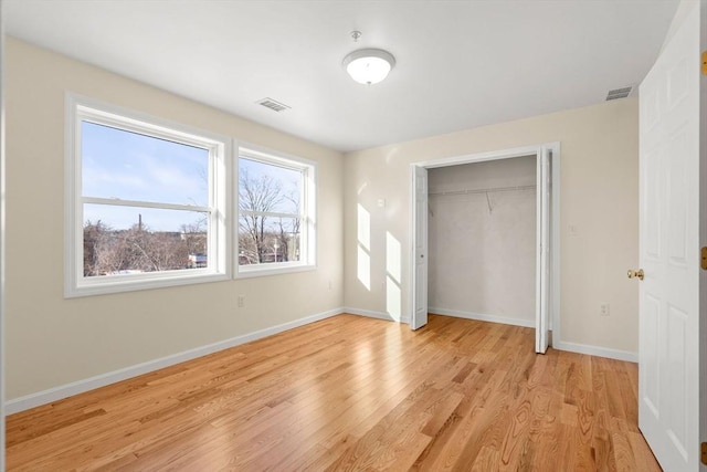 unfurnished bedroom featuring light wood-style floors, baseboards, and a closet