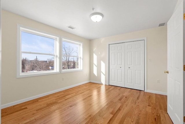 unfurnished bedroom with light wood finished floors, a closet, and baseboards