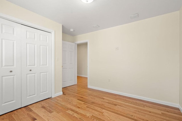 unfurnished bedroom featuring baseboards, light wood-style floors, and a closet