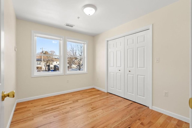 unfurnished bedroom with light wood finished floors, baseboards, and a closet