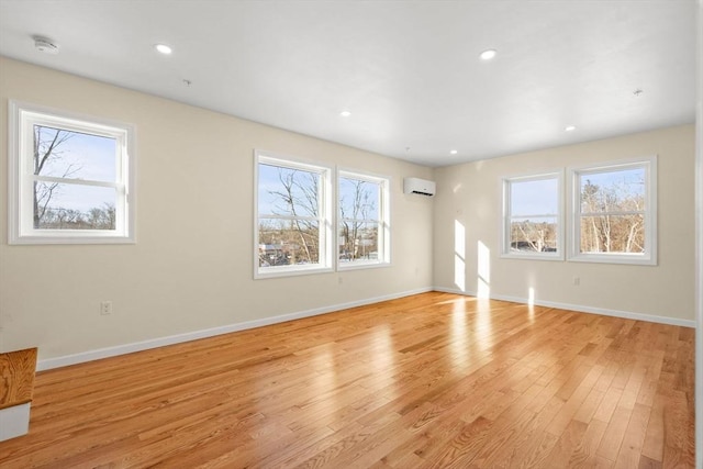 unfurnished living room with light wood-type flooring, a wall mounted AC, baseboards, and recessed lighting