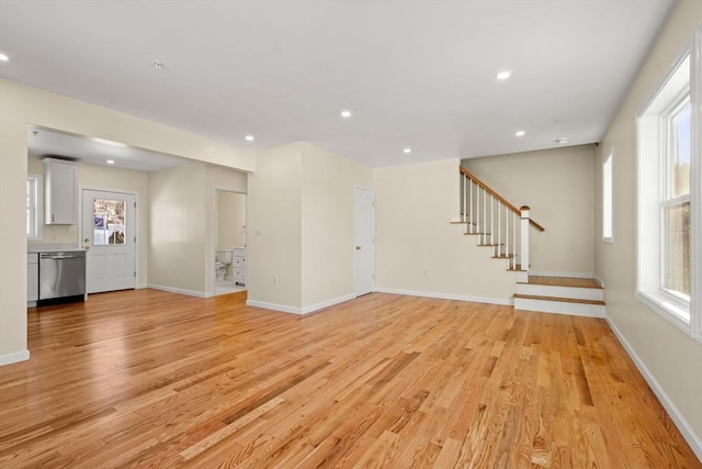 unfurnished living room featuring light wood-style flooring, stairway, healthy amount of natural light, recessed lighting, and baseboards