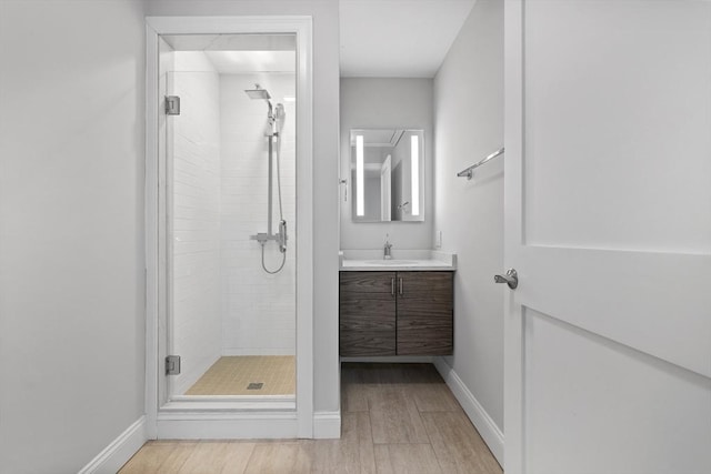 bathroom with vanity, a shower with shower door, and hardwood / wood-style floors