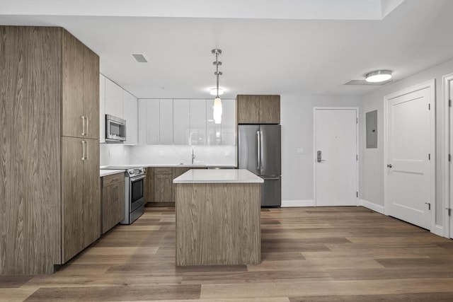 kitchen with a center island, electric panel, pendant lighting, stainless steel appliances, and decorative backsplash