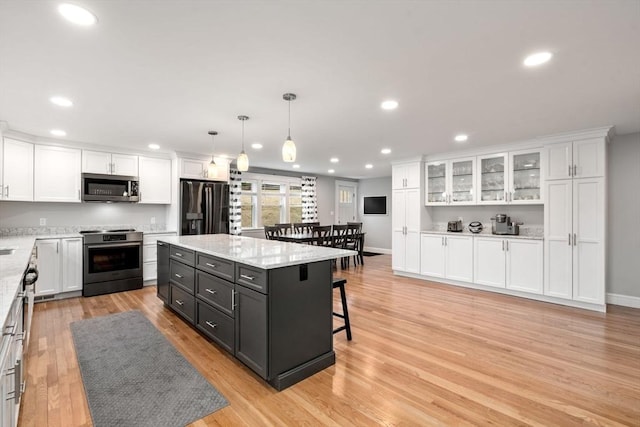 kitchen featuring appliances with stainless steel finishes, a breakfast bar, white cabinetry, and light wood-style flooring