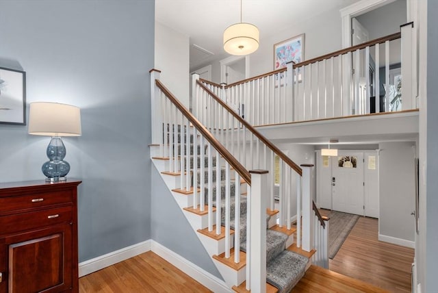 stairs with a high ceiling, baseboards, and wood finished floors