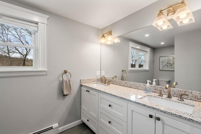 full bath with baseboards, a sink, baseboard heating, and double vanity