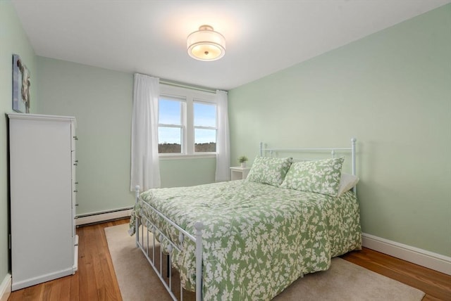 bedroom with baseboards, baseboard heating, and wood finished floors