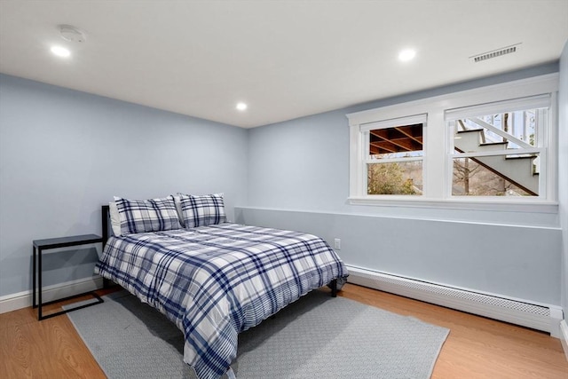 bedroom with recessed lighting, visible vents, baseboard heating, wood finished floors, and baseboards