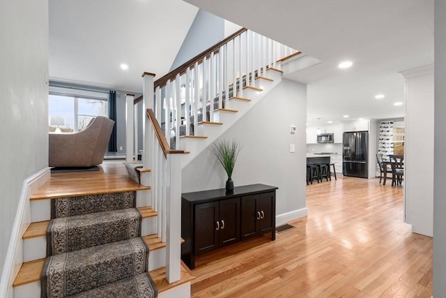 stairs with recessed lighting, visible vents, a baseboard heating unit, wood finished floors, and baseboards