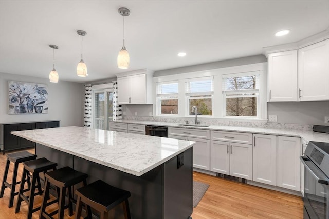 kitchen featuring dishwashing machine, white cabinets, a sink, black oven, and a kitchen breakfast bar