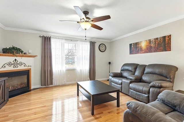 living area featuring crown molding, a ceiling fan, baseboards, and light wood-type flooring