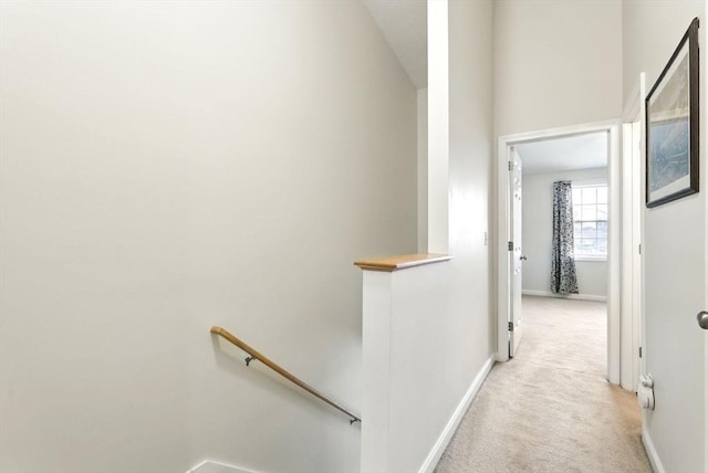 corridor featuring light colored carpet, baseboards, and an upstairs landing