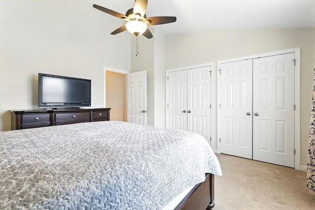bedroom featuring multiple closets, ceiling fan, light carpet, and high vaulted ceiling