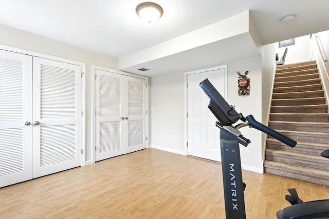 exercise room featuring baseboards, visible vents, and wood finished floors