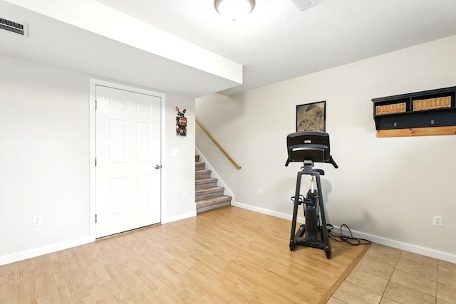 workout area featuring baseboards, light wood finished floors, and visible vents