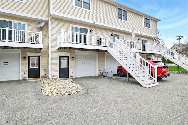 view of front facade featuring stairway, an attached garage, and driveway