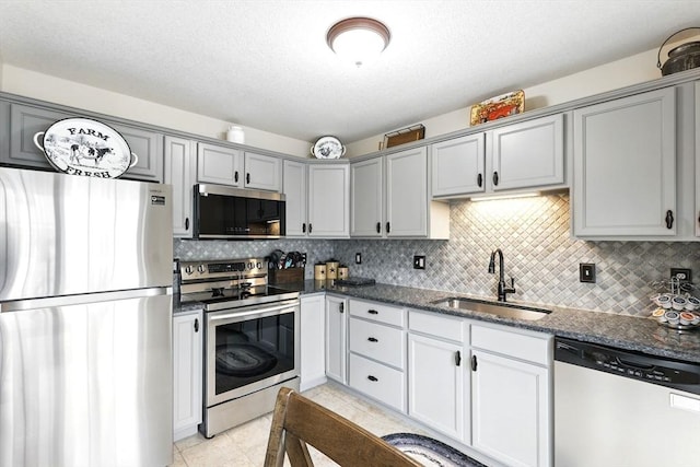 kitchen featuring a sink, gray cabinets, stainless steel appliances, and tasteful backsplash