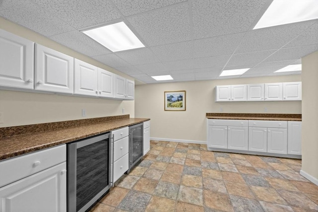 21 Gramps Way, Chatham, MA 02659 - kitchen featuring beverage cooler, a drop ceiling, dark countertops, and white cabinetry