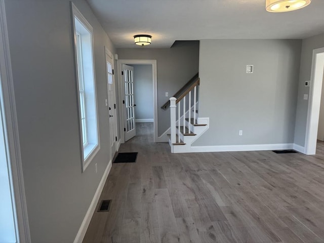 foyer entrance featuring visible vents, stairs, baseboards, and wood finished floors