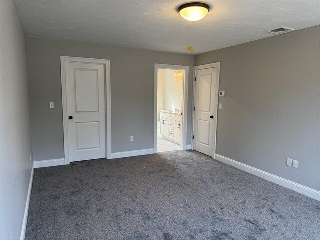 unfurnished bedroom with carpet, connected bathroom, visible vents, and baseboards