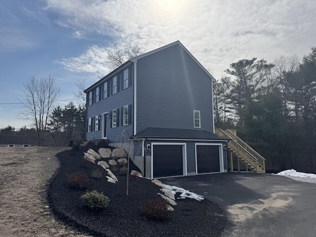 view of side of home featuring stairs, driveway, and an attached garage