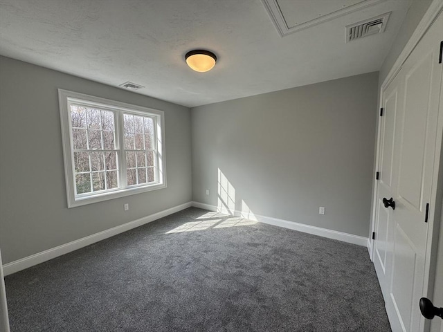 unfurnished room with baseboards, visible vents, dark carpet, and attic access