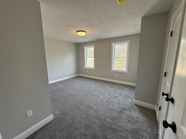 unfurnished bedroom with dark carpet, a textured ceiling, and baseboards