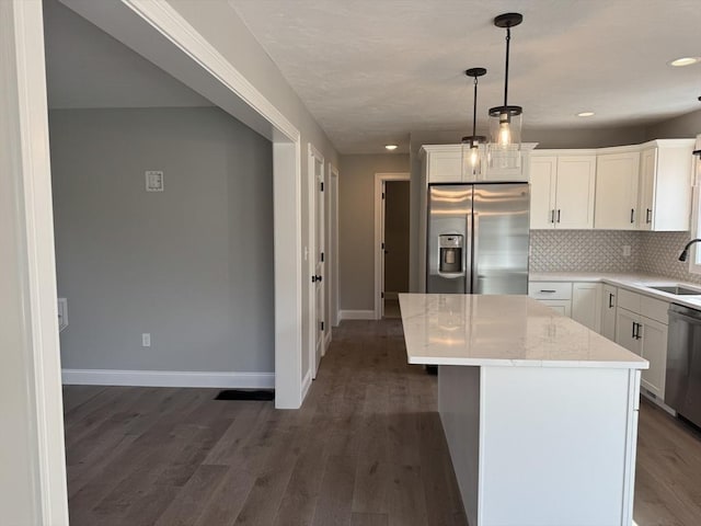 kitchen with white cabinets, dark wood finished floors, appliances with stainless steel finishes, a sink, and backsplash