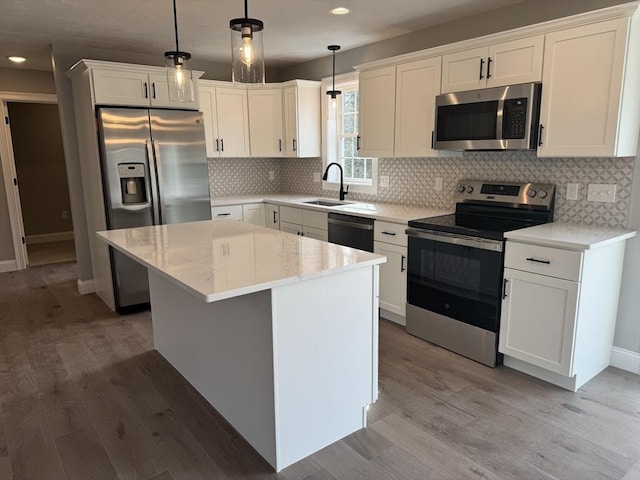 kitchen with white cabinets, light wood-style flooring, appliances with stainless steel finishes, a sink, and backsplash