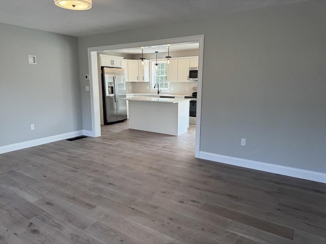 kitchen with appliances with stainless steel finishes, open floor plan, backsplash, and wood finished floors