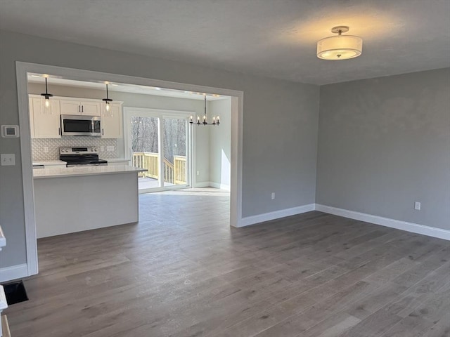 kitchen with tasteful backsplash, appliances with stainless steel finishes, dark wood-type flooring, open floor plan, and white cabinets