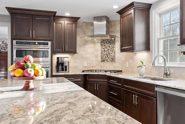 kitchen with backsplash, wall chimney range hood, sink, light stone countertops, and appliances with stainless steel finishes