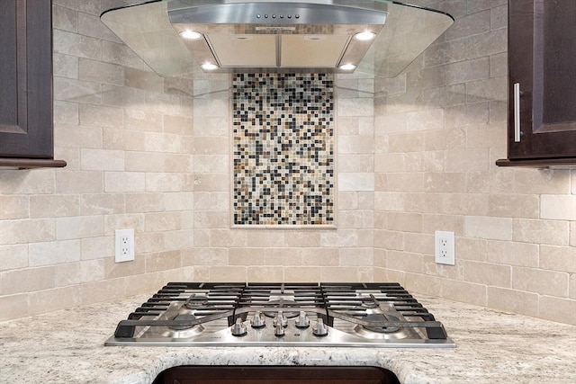 kitchen featuring light stone countertops, dark brown cabinets, backsplash, and stainless steel gas cooktop