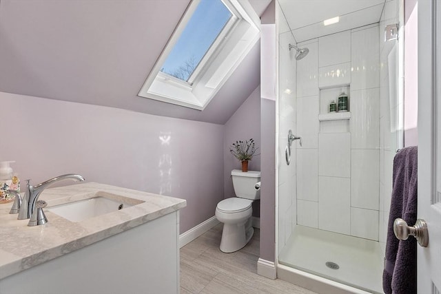 bathroom with a tile shower, toilet, vanity, and lofted ceiling with skylight