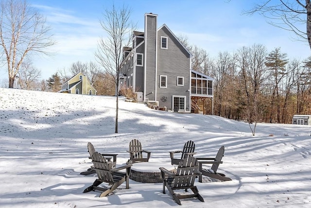 snow covered back of property with a sunroom